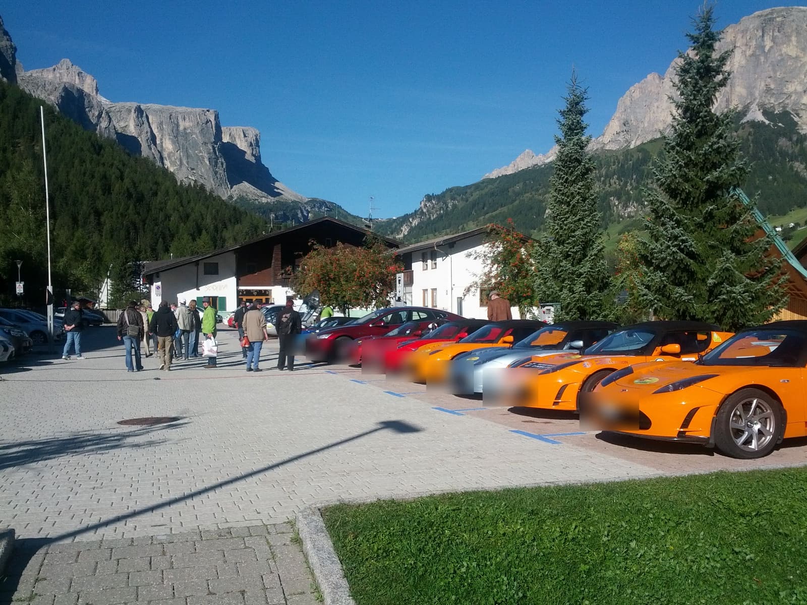 Reihe farbiger Tesla Roadster auf einem Dorfplatz in den Dolomiten