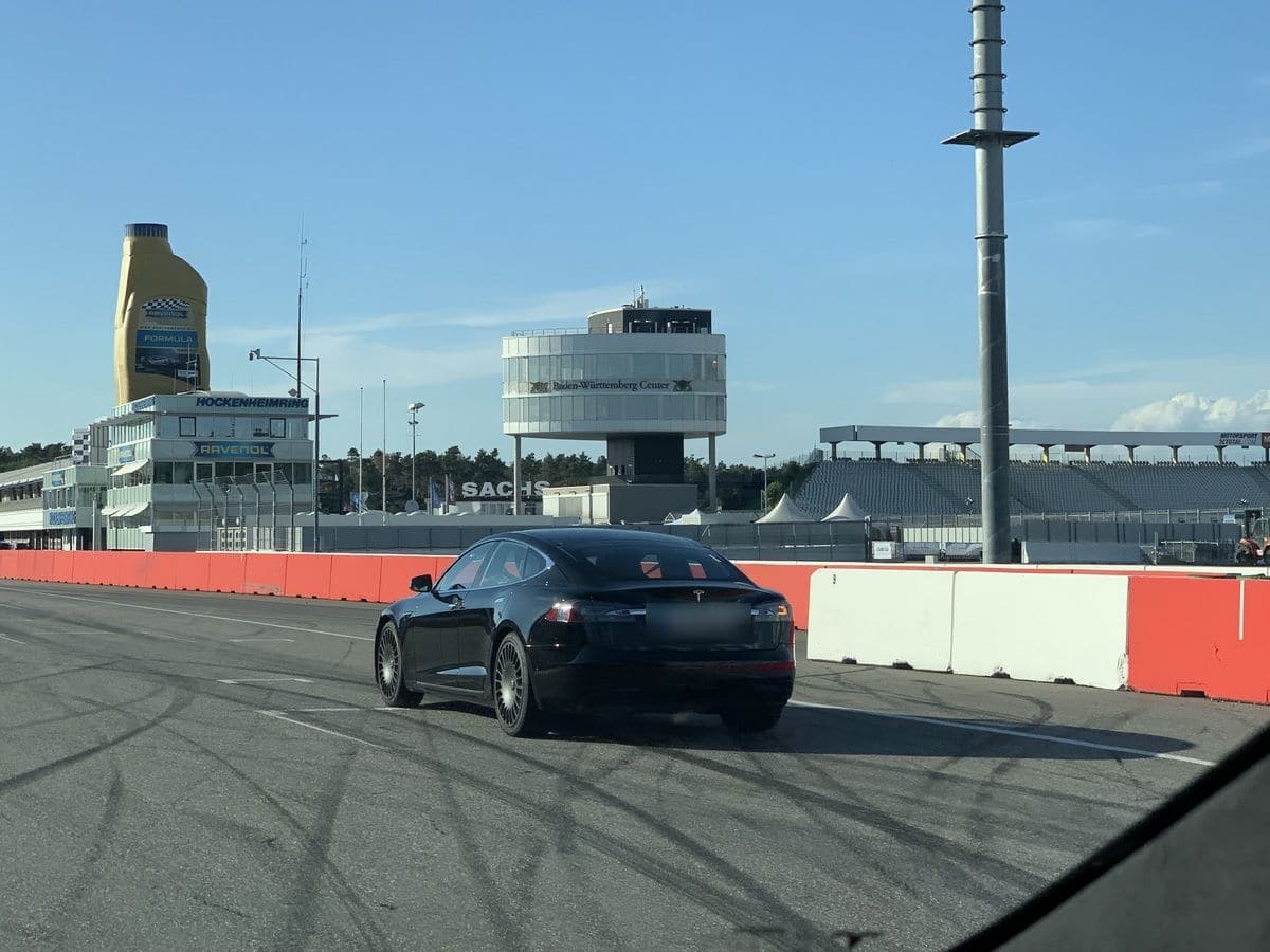 Schwarzer Tesla auf der Start-Ziel-Geraden des Hockenheimrings, im Hintergrund leere Tribünen