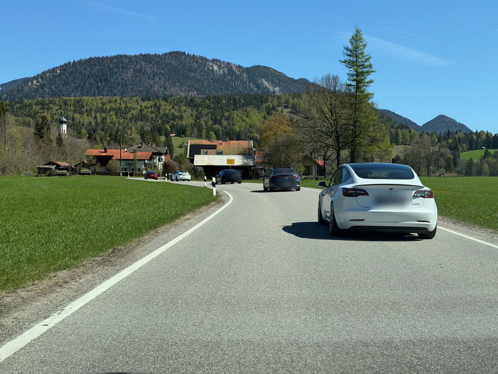 Roter Model 3 auf der Landstraße, dahinter der Konvoi