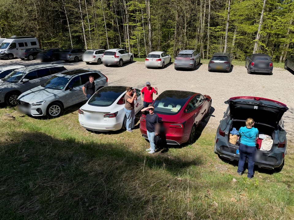 Fahrzeuge auf einem Parkplatz am Berg, Teilnehmende packen aus