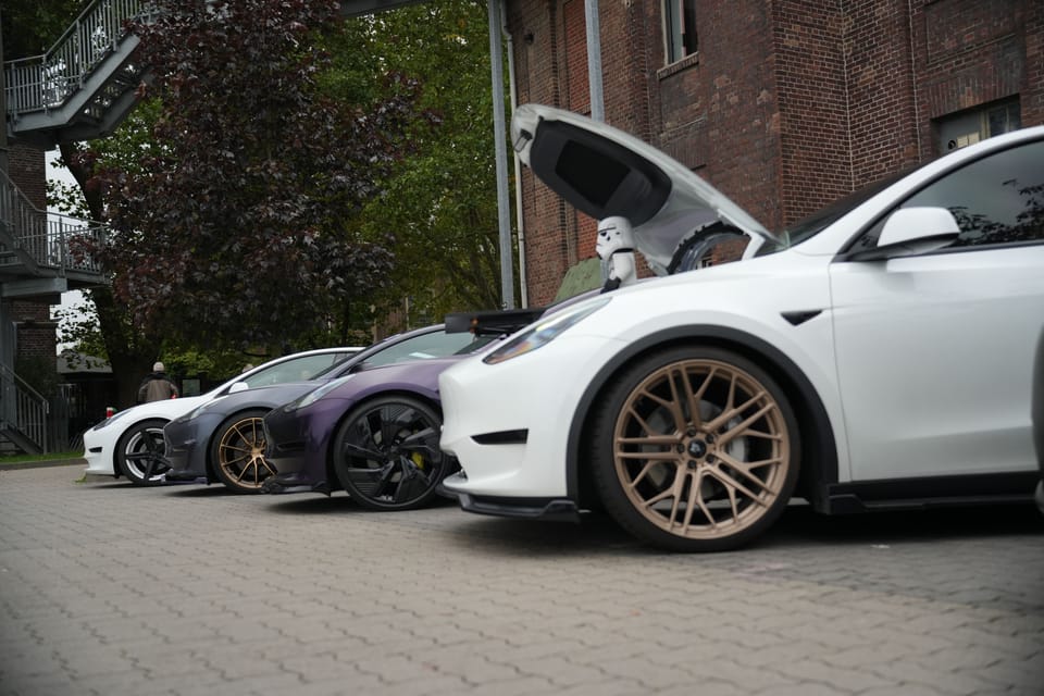 Ein Model X mit geöffneten Flügeltüren zwischen anderen Fahrzeugen
