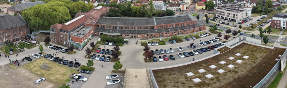 Panorama über das Zechengelände mit Parkflächen und den Backsteinbauten