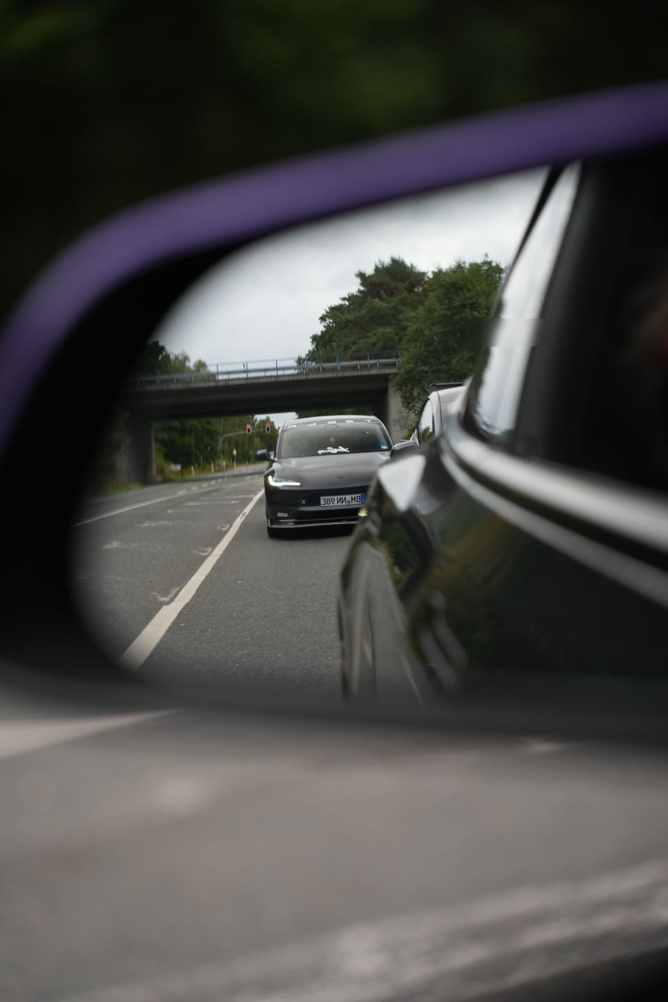 Blick in den Außenspiegel während der Anfahrt, dahinter weitere Teslas
