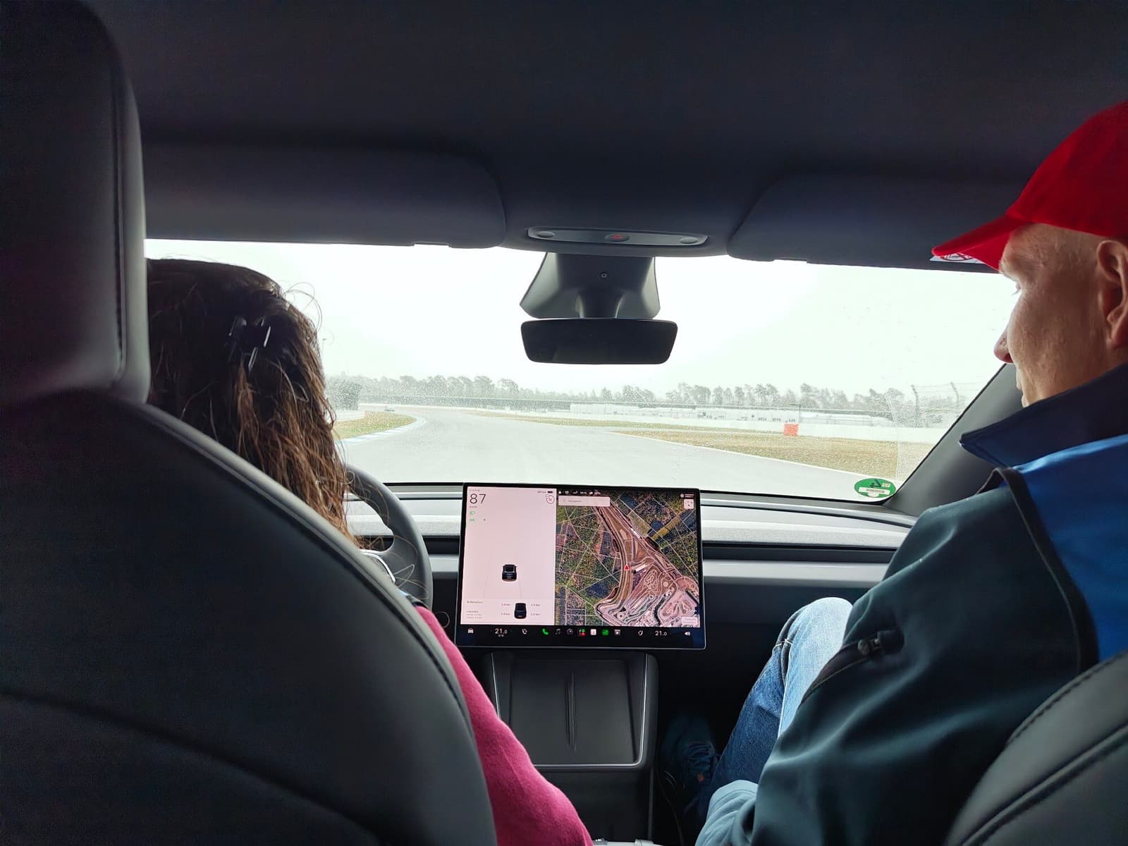 Blick von der Rückbank eines Tesla auf die Strecke, auf dem Bildschirm die Streckenkarte des Hockenheimrings