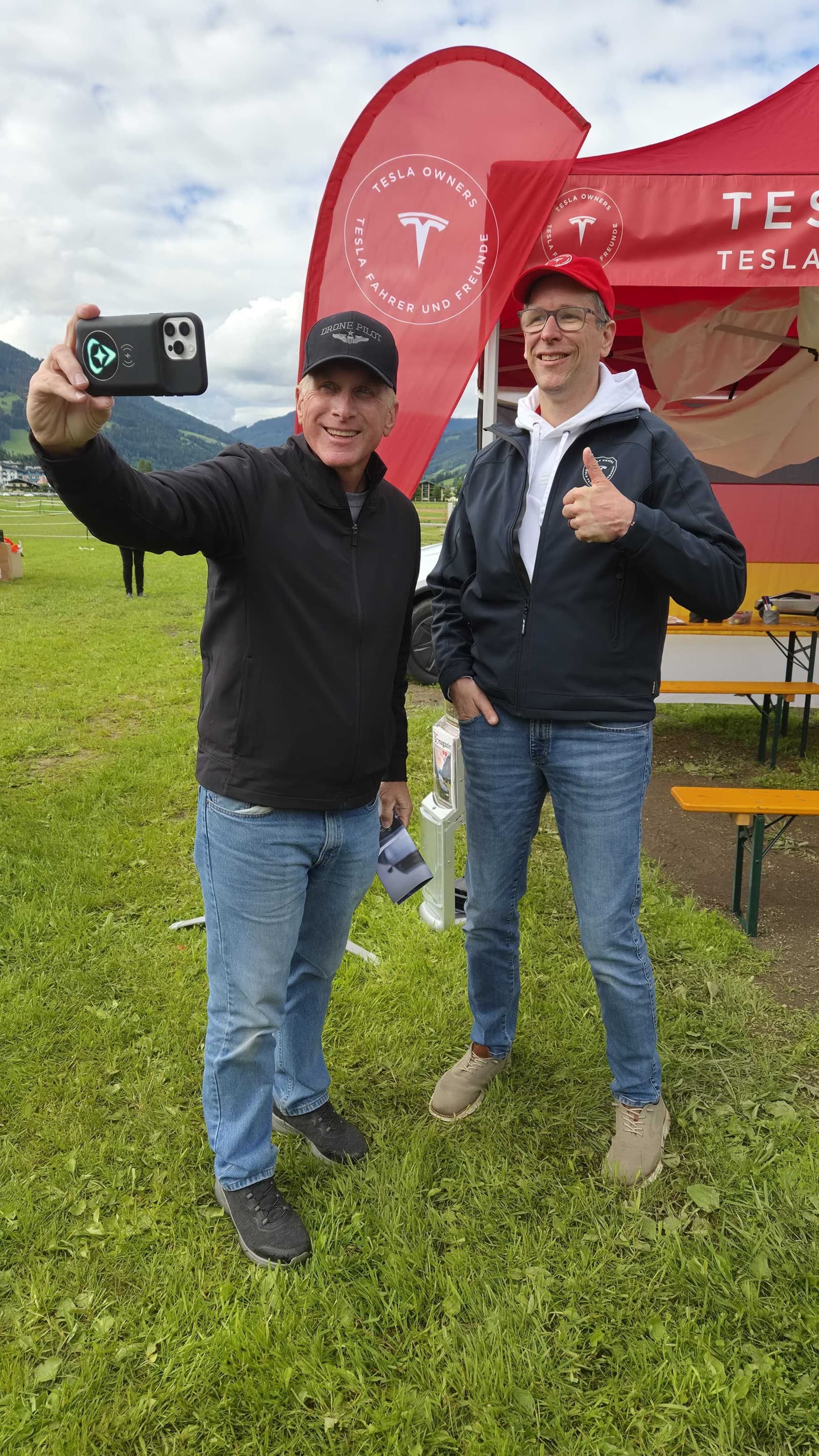 Zwei Vereinsmitglieder vor der Fahne des TFF e.V. am Vereinsstand, einer hält ein Telefon für ein Selfie hoch