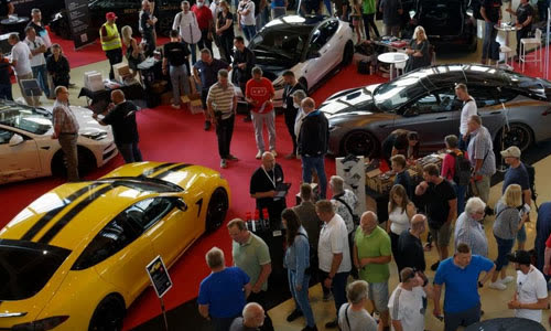 Besucher zwischen ausgestellten Elektrofahrzeugen in einer Messehalle