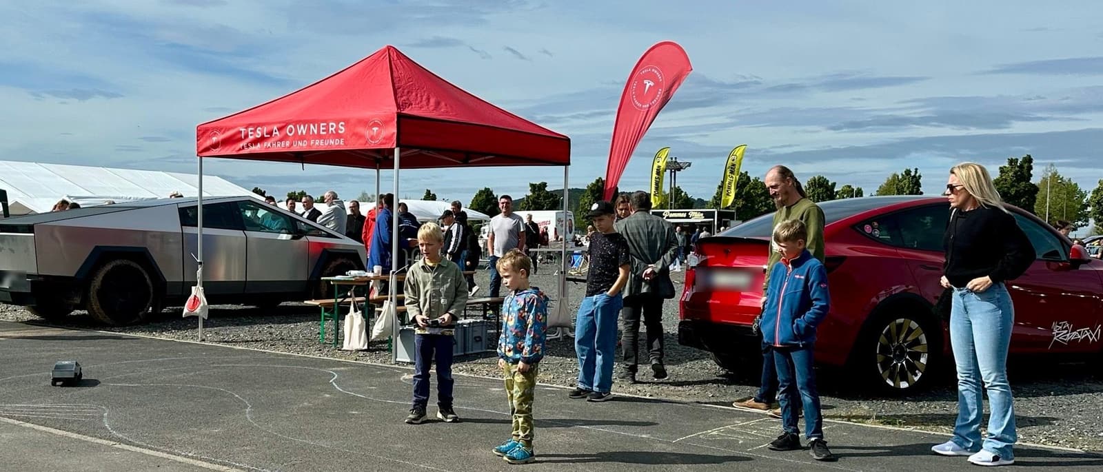 Kinder steuern die ferngesteuerten Cybertrucks vor dem Vereinsstand, dahinter der echte Cybertruck