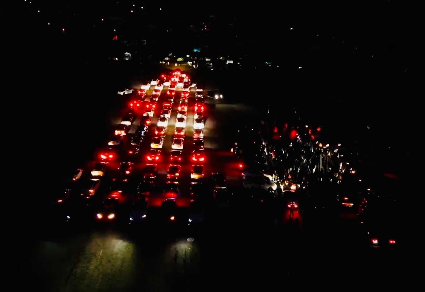 Luftaufnahme der Lightshow: Fahrzeugreihen mit roten Rücklichtern in der Dunkelheit