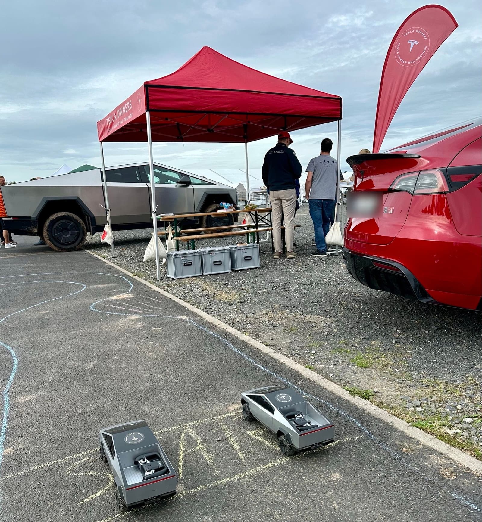 Der Vereinsstand mit Pavillon, Cybertruck und zwei ferngesteuerten Modellen auf der mit Kreide gezeichneten Strecke