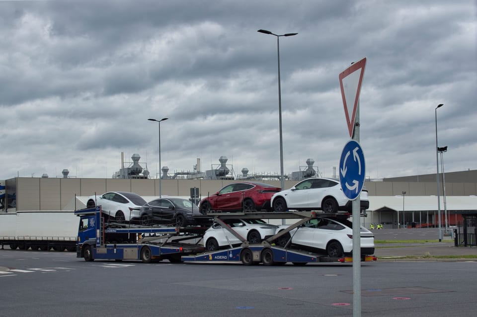 Autotransporter mit fertigen Fahrzeugen vor dem Werk