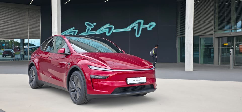 Roter Model Y vor der dunklen Fassade mit dem Giga-Schriftzug