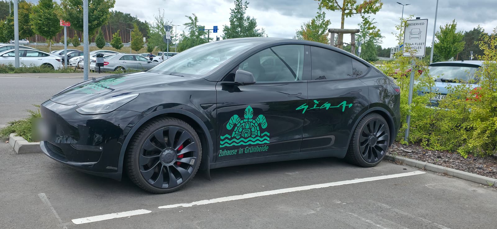 Weißer Model Y mit dem Schriftzug „We are Giga, the future" auf dem Werksparkplatz