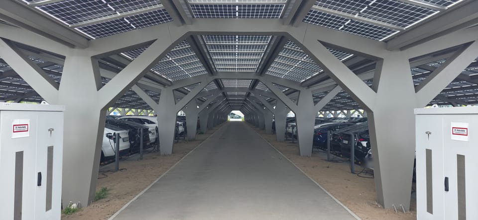Blick durch eine Gasse überdachter Ladeplätze unter Solarmodulen