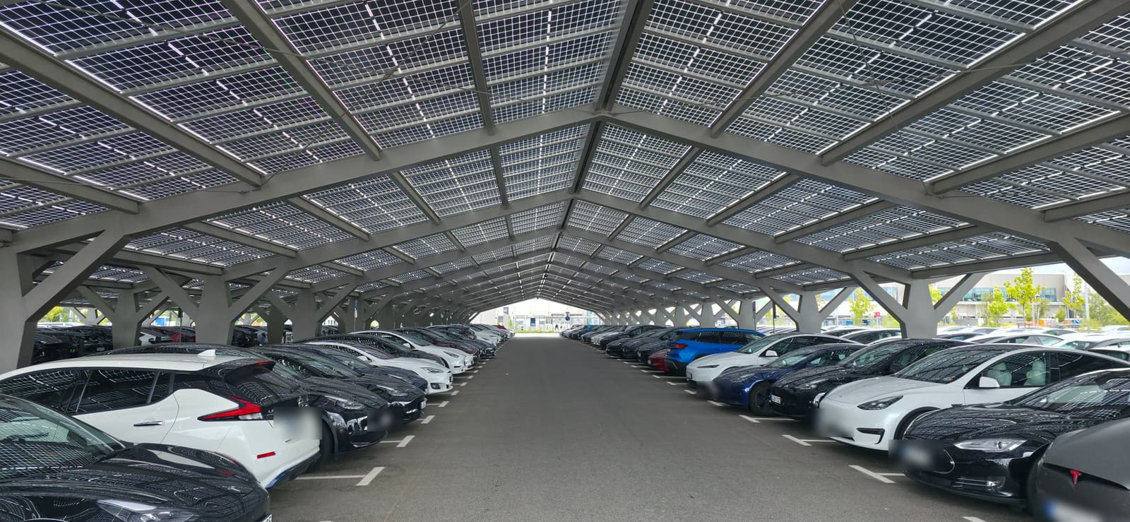 Reihe überdachter Ladeplätze unter Solarmodulen auf dem Werksgelände
