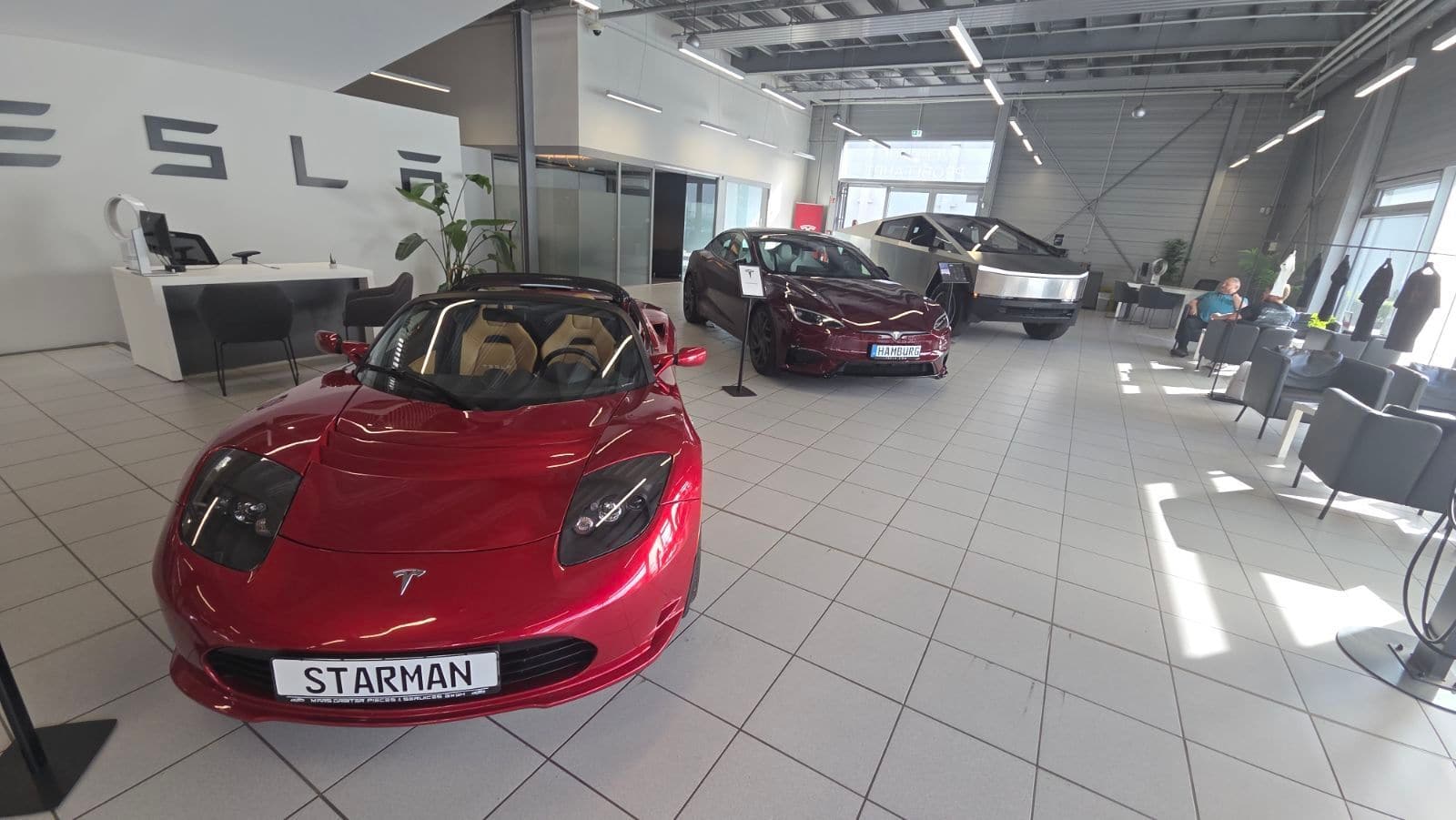 Ausstellungsraum des Tesla Center Wandsbek, vorne ein roter Tesla Roadster, dahinter ein weinroter Model S Signature und ein Cybertruck