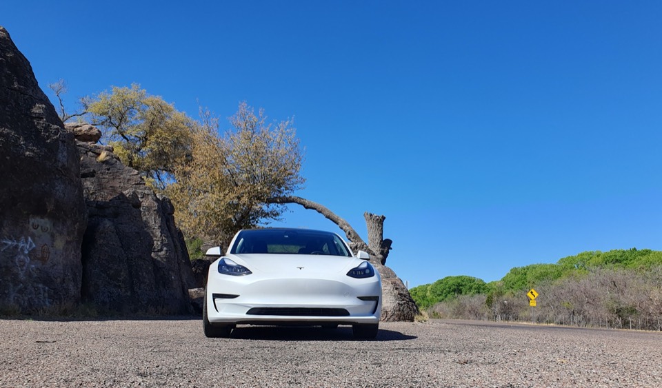 Weisses Tesla Model Y vor Felsen in trockener Landschaft