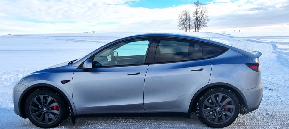 Silbernes Tesla Model Y auf einer verschneiten Ebene